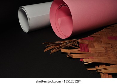 White And Pink Paper Rolls And Woven Bambo On Black Background