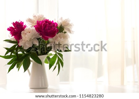 White and pink peonies in vase on white table. Horizontal, copy space