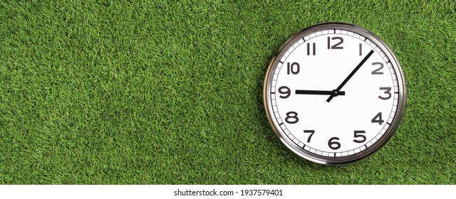 White Plain Analogue Wall Clock On Green Turf Grass Background. Five Past Nine Oclock. Copy Space, Game Time Management Concept. Opening Or Closing Hours. Ecological Sustainable Business Banner