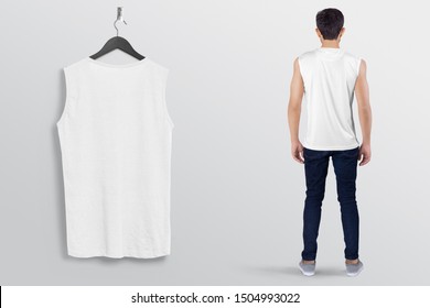 White Plan Sleeveless Shirt On A Man Male Model In Black Denim Jeans Pant, Isolated, Mockup. Hanging White Blank Sleeveless Shirt Shirt, Against Empty Wall.