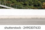 White plaster fence with flowering garden and  a staircase on behind. Cement sidewalk and street in front. Background for copy space.