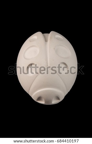 White plaster figurine beetle ladybug on black background