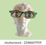 White plaster statue head of David  with big eyes and glasses green background. 