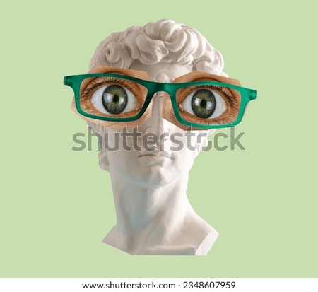 White plaster statue head of David  with big eyes and glasses green background. 