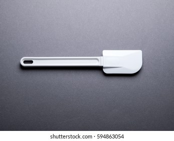 White Plastic Baking Spatula On Dark Gray Background