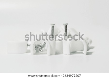 White Plastic Cable Clips And Nails On A White Background