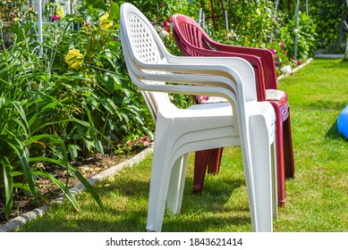 White Plastic Chair On Green Grass In Summer Garden