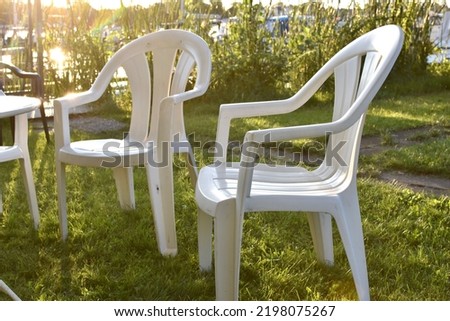 white plastic chairs stand on green grass in the garden