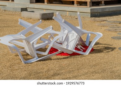 White Plastic Chairs Turned Over On Top Of Red Plastic Table.