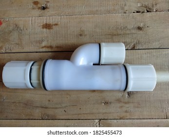 White plastic check valve isolated on wooden board. Check valve in water pipes to prevent reverse flow of water.