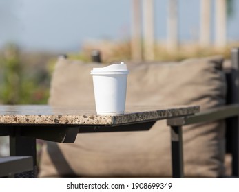 White plastic coffee cup and background are blurred.