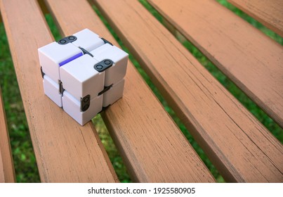 A white plastic cube on a wooden bench. An infinity cube for relaxation.