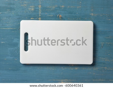 white plastic cutting board on blue wood table, top view