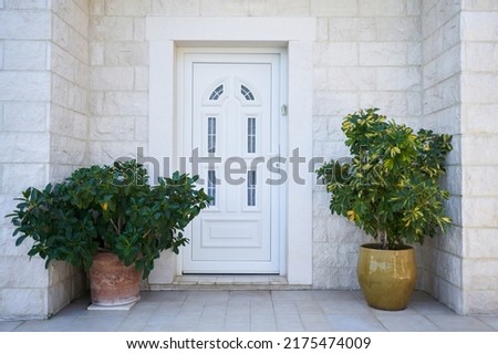White plastic entrance door and facade decorations with plants