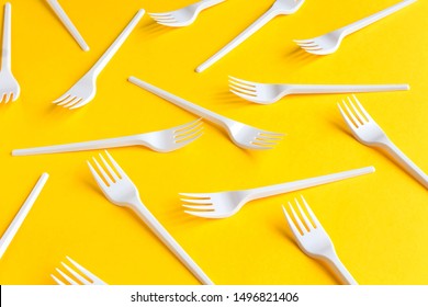 White Plastic Forks On Vibrant Yellow Background. Fast Food, Eco And No Plastic Concept. Open Composition.