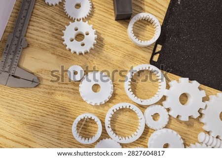 White plastic gear prototypes and measuring tools on a wooden workbench, seen from above