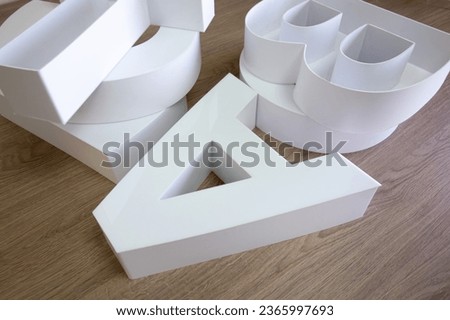 White plastic letters lie on a wooden table. Assemble the logo.Three-dimensional white letters on the table. Language training. [[stock_photo]] © 