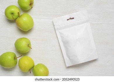 White plastic pouch bag with apples on wood table. Mock-up template for design. 3d rendering illustration.