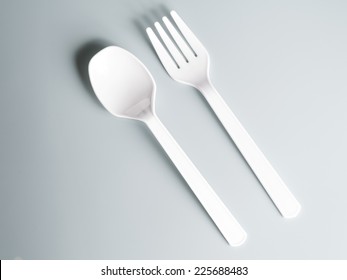 White Plastic Spoon And Fork On Gray Background