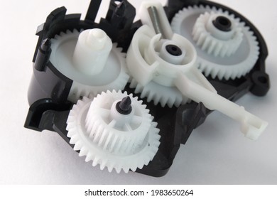 white plastic spur gears connected in complex mechanism, part of the inkjet printer paper feeder mechanical drive