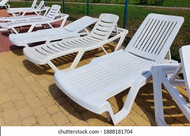 White Plastic Sun Loungers In Front Of Pool. No People, Front View