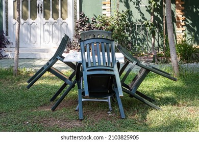 The White Plastic Table With Four Green Chairs Are Outside By The House In The Garden