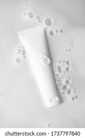 White Plastic Tube Mockup With Moisturizer Cream, Shampoo Or Facial Cleanser In Water With Gentle Soap Foam Bubbles, Top View.