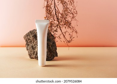 White Plastic Tube And Stone And Natural Dry Herb Creative Still Life Cosmetic Photography. Lip Balm Blank Empty Mockup