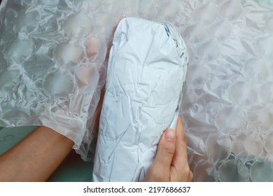 White Plastic Wrapped With Fragile Items Inside That Packaging With Plastic Air Bubble Wrapped By Hands, Ready To Putting In Parcel Box.