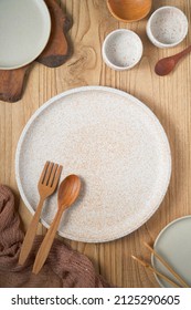 White Plate And White Bowl With Orange Abstract Motif And Small Plate With Wooden Cutlery Ready To Serving Any Kind Of Food On Wooden Table.                 