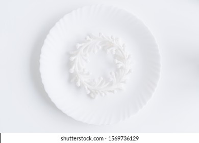 White Plate And Christmas Wreath Top Down View. Traditional Round Empty Dish Isolated On White Background Above Shot. Tableware Decoration For Festive Seasonal Holiday.Winter Decor For Kitchen