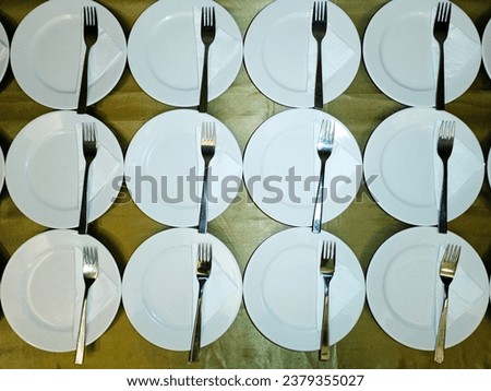 a lot of white plate and fork arranged on the table read to served. Surabaya, East Java, Indonesia. October 02, 2022