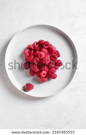 White plate with fresh rasberries. Top view food. 