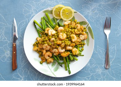 White Plate With A Grilled Asparagus, Shrimp And Pea Salad With A Fork And A Knife On A Blue Tablecloth.