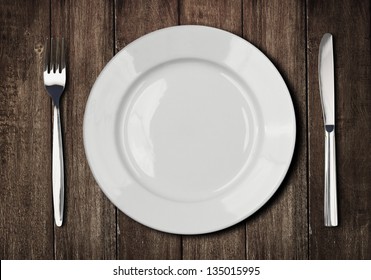 white plate, knife and fork on old wooden table - Powered by Shutterstock