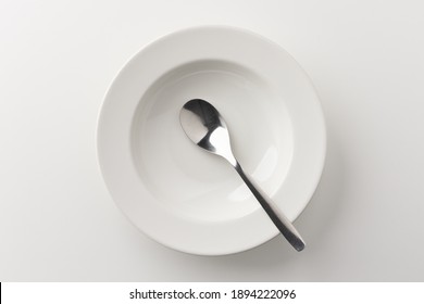 A White Plate On A White Table With A Spoon There Is No Food On The Plate. Household Equipment