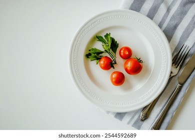 White plate with red cherry tomatoes and green parsley on a striped napkin with a fork and knife. - Powered by Shutterstock