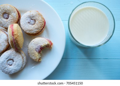 White Plate Of Round Cookies With Glass Of Milk. One Cookie Bitten. Top Shot