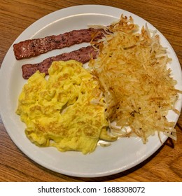 White Plate With Scrambled Eggs, Turkey Bacon And Hash Brown Potatoes.