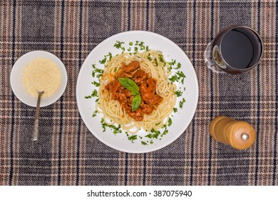 White Plate With Spagetti Bolognese, Glass Of Wine And Bowl Of Parmesan. View From Above.