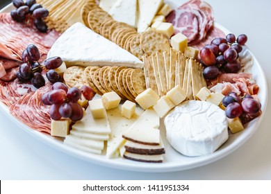 White Platter Of Cheese And Meats And Crackers On A White Background