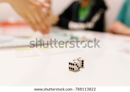 White Playing dice on a table with people in background playing boardgame