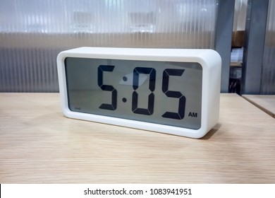 White pocket digital clock on wooden shelf for decoration