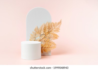 White podium with branch of leaves and arch to show cosmetic products. Beige color background for branding and packaging presentation.