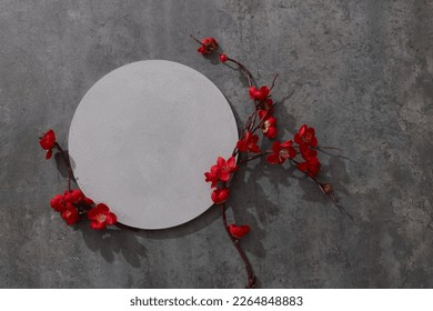 White podium for product presentation with red flowers on gray background. Empty cylindrical platform for cosmetic. Mockup with concrete circle and copy space