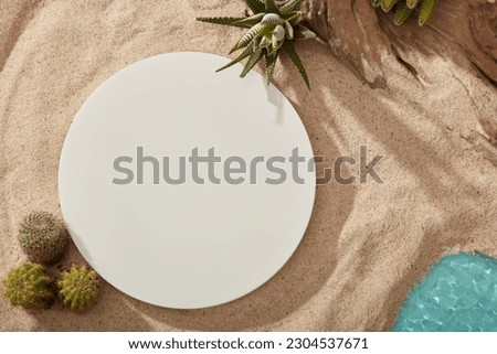 White podium in round-shaped displayed on sea sand with a lake and Cacti. Empty space on podium to show your product