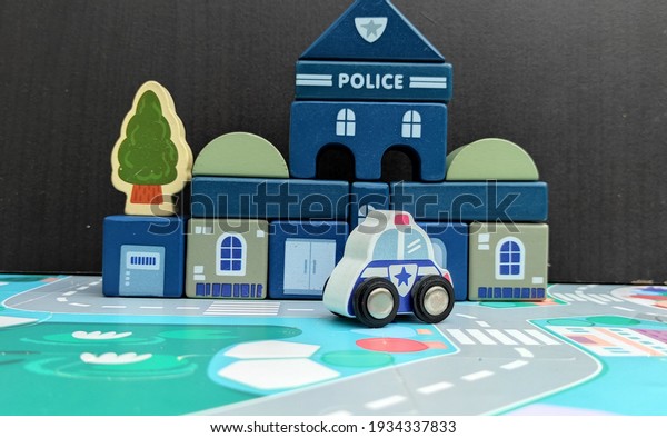 a white police patrol vehicle\
with police office station bulding and black wooden\
background\
