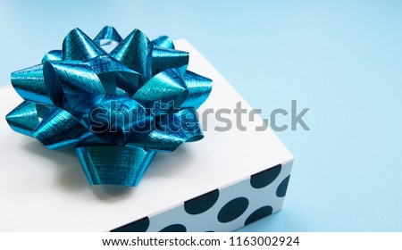 White polka dot pattern gift box on a blue  background, decorated with a blue bow, creating a romantic atmosphere. Typically used for birthday, anniversary presents, gift cards, post cards.