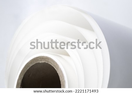 White polygraph paper on a cardboard core. A bundle of leftover paper in a printing house. Material for the printing industry. Selective focus