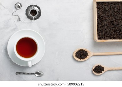 White Porcelain Cup Of Tea, Small Silver Spoon, Teapot Used For Brewing Loose Leaf Tea 
Wooden Box Spoons On Grey Concrete Background. Food, Beverage Background. 
Horizontal Orientation, Top View.